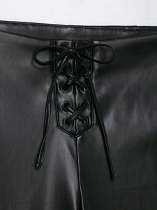 Detailed view of the lace-up eyelet design on black faux leather flared trousers