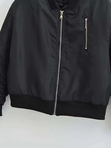 Detail einer schwarzen Bomberjacke mit silbernen Reißverschlüssen und Rippstrickkragen