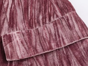 Macro shot of dusty rose velvet fabric showing detailed vertical pleats and soft texture