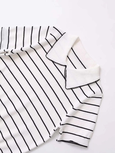 Detail of knit polo shirt featuring black stripes and elegant scalloped lace trim
