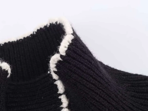 Macro detail of black ribbed knit fabric featuring decorative white wavy edge trim