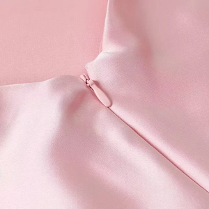Close-up of invisible zipper detail on pink satin midi dress with silky fabric texture