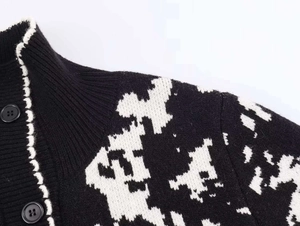 Detail of high-contrast jacquard knit texture with black buttons and stand-up collar