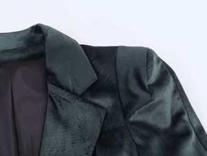 Détail du blazer en velours vert foncé avec col à revers et texture de tissu lisse