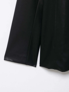 Close-up detail of premium black PU leather fabric showing texture and stitching on a blazer