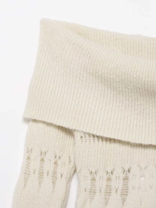Détail macro d'un pull en maille crème montrant la texture côtelée et ajourée