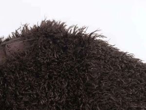 Close-up detail of plush deep brown curly faux fur fabric with a soft textured finish
