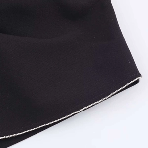 Detail eines schwarzen Rocksaums mit Silber-Strassbesatz und hochwertigem Gewebestoff