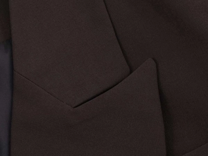 Detail of deep brown double-breasted blazer showing fine twill texture and collar stitching