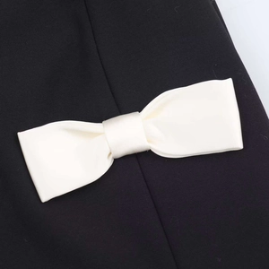 Detailed view of an ivory satin bow on a high-quality black sleeveless V-neck dress
