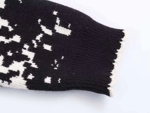 Detail of knit sweater ribbed cuff with black white jacquard pattern and wavy trim edge