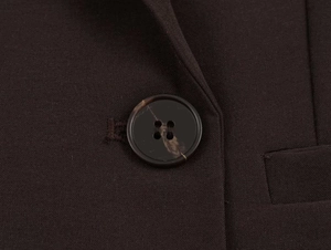 Detail of amber texture button and stitching on a dark brown double-breasted blazer