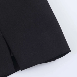 Close-up of black woven dress fabric showing precise slit detail and stitching texture