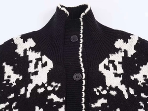 Detail of high stand collar and black buttons on a chunky jacquard knit sweater