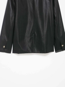 Detail of black faux leather jacket back featuring back seam and buttoned cuffs