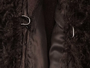 Close-up of the metal hook-and-eye closure on dark brown curly faux fur winter coat