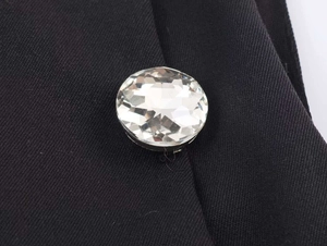 Macro shot of a faceted crystal button on a premium black twill strap top detail