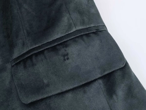 Détail macro d'une poche de blazer en velours vert foncé avec texture à fines côtes