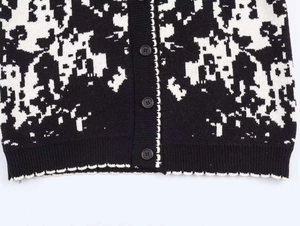 Close-up of contrast jacquard knit cardigan with black buttons and wavy dot pattern hem