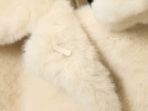 Macro detail of creamy faux fur texture and matching snap button on elegant autumn coat