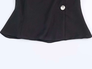 Detail of elegant black top hem featuring a sparkling rhinestone button and ruffles