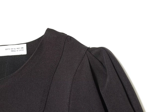 Detail of black pleated shoulder and puff sleeve with fabric texture and size label