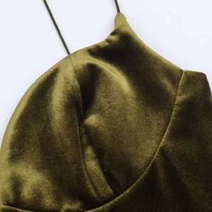 Detail of olive green velvet dress showing fine straps and textured structured neckline