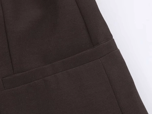 Close-up of dark brown suit fabric showing refined stitching and smooth pocket edge
