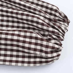 Dettaglio della manica di camicia a quadri marrone con polsini elastici e trama fine