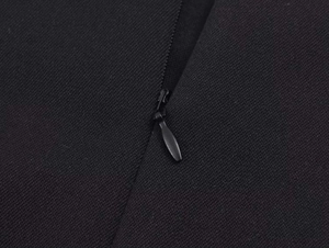 Close-up detail of a black top showing high-quality invisible zipper and woven fabric texture