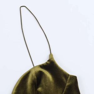 Detail of dark green velvet fabric texture and thin spaghetti strap on summer dress