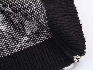 Detailed close-up of geometric jacquard knit pattern with ribbed edges and thick texture