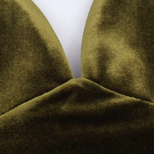 Detail of olive green velvet fabric showing V-neckline stitching and premium texture