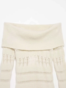Détail du pull en maille blanc cassé à épaules dénudées avec motifs ajourés