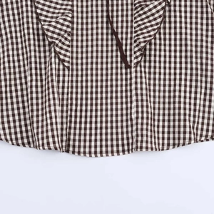 Dettaglio camicia a quadretti vichy marroni con orlo a balze e finiture decorative