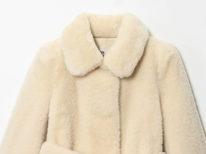 Detailed close-up of a cream faux fur coat featuring a large lapel and soft texture