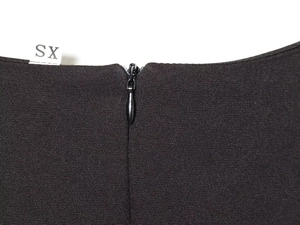 Detailed macro view of invisible zipper and size XS tag on black pleated dress