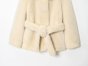Detailed texture of beige faux fur coat featuring a soft belt tie on a clean white background