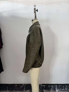 Side view detail of dark olive green leather jacket with elastic hem on a mannequin
