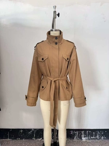 Detail eines khakifarbenen Trenchcoats mit großen Pattentaschen, Knöpfen und Taillengürtel