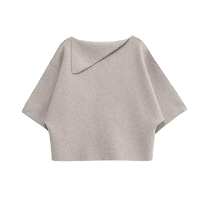 Detail of light grey knit top featuring asymmetrical lapel collar and soft batwing sleeves