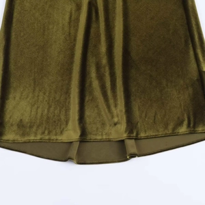 Detailed close-up of dark green velvet hem showing premium texture and stitching