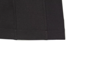 Detailed view of vertical seams and double-stitched hem on black pleated short dress