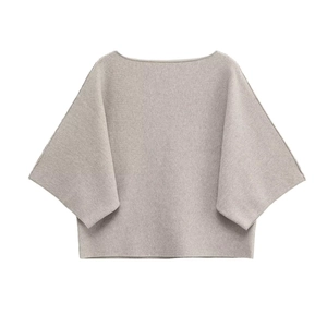 Detail of light grey knit sweater featuring flat-lay boat neck and batwing sleeve texture