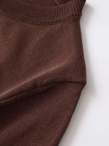 Detailed view of the ribbed round neckline and shoulder seams of a dark brown knit cardigan