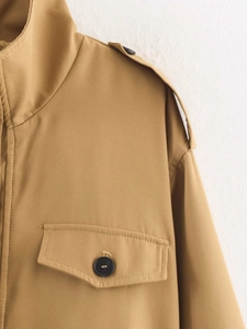 Detailansicht eines khakifarbenen Trenchcoats mit Schulterklappen und Pattentaschen
