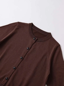 Detail view of a dark brown knit cardigan with elegant black buttons and round neckline