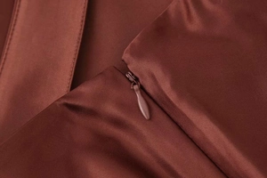 Close-up of the invisible zipper and smooth satin fabric on this elegant rust red skirt