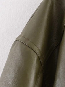 Detail of olive green faux leather jacket featuring stitching and lychee grain texture