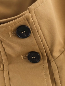 Makroaufnahme von khakifarbenem Trenchcoat-Stoff mit schwarzen Knöpfen und Köperbindung